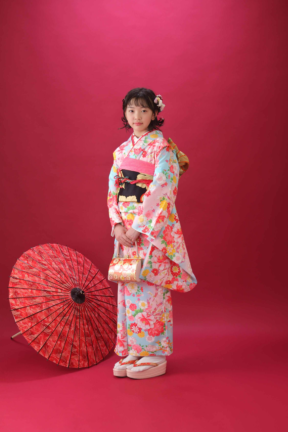 赤い着物で傘を持って記念撮影をする女の子